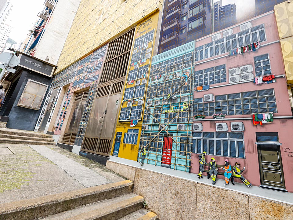 Jaune创作的彩色街头壁画，以竹棚架覆盖的建筑为主题。