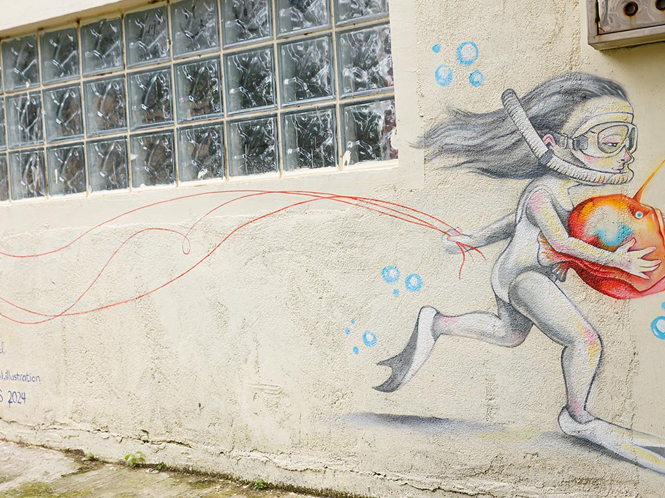 Nicole Roquel创作的壁画，描绘了一个孩子在水中拿着一个大苹果奔跑的场景。 