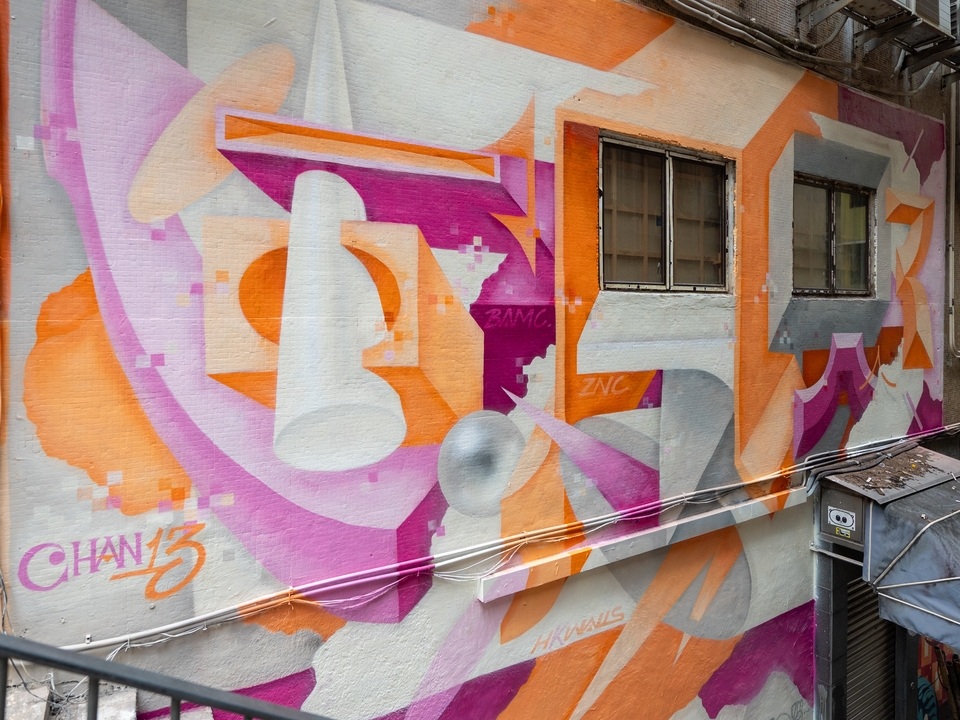 陈十三在四方街创作的紫色、橙色、白色和灰色壁画。 