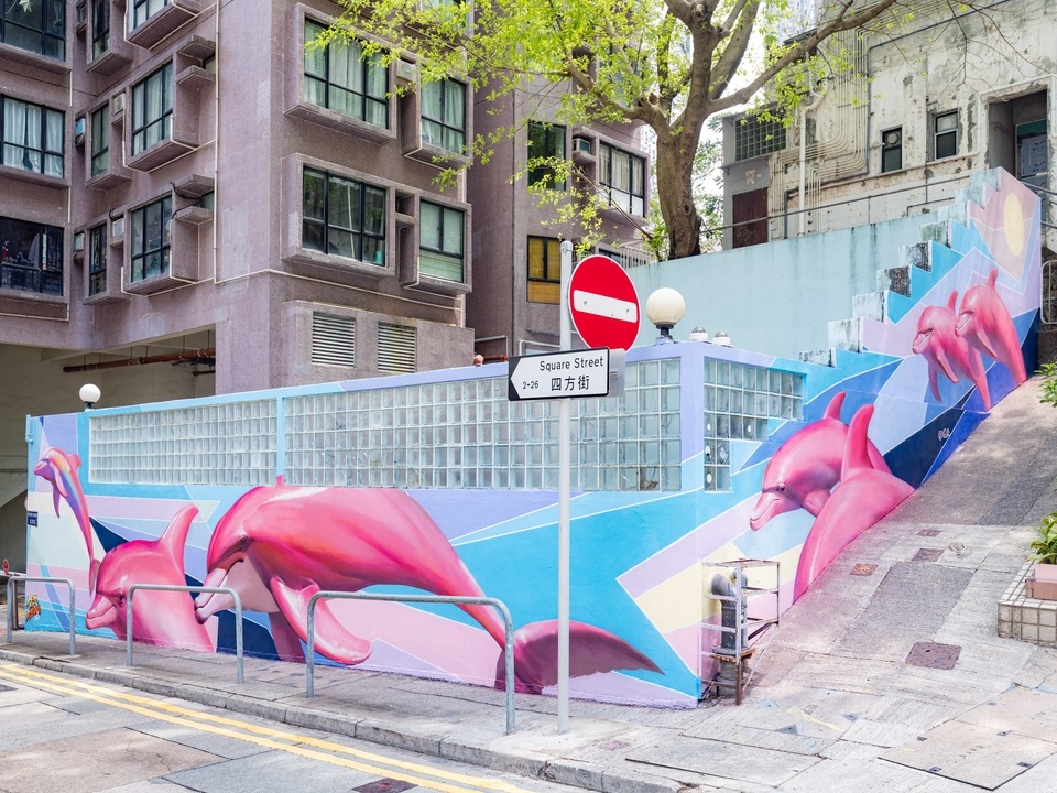 XEVA创作的粉红色海豚壁画横跨四方街的一面墙。